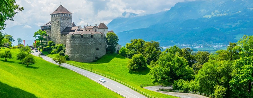 Castle In The Middle Of Green Landscape With Mountains In The Background